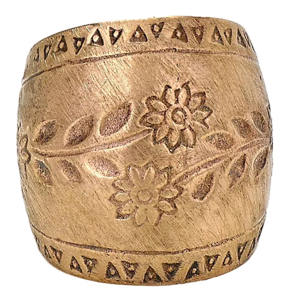 A wide, cylindrical metallic cuff bracelet in a warm gold or bronze tone, featuring engraved floral motifs and geometric triangle borders at the top and bottom, shown on a plain light background.