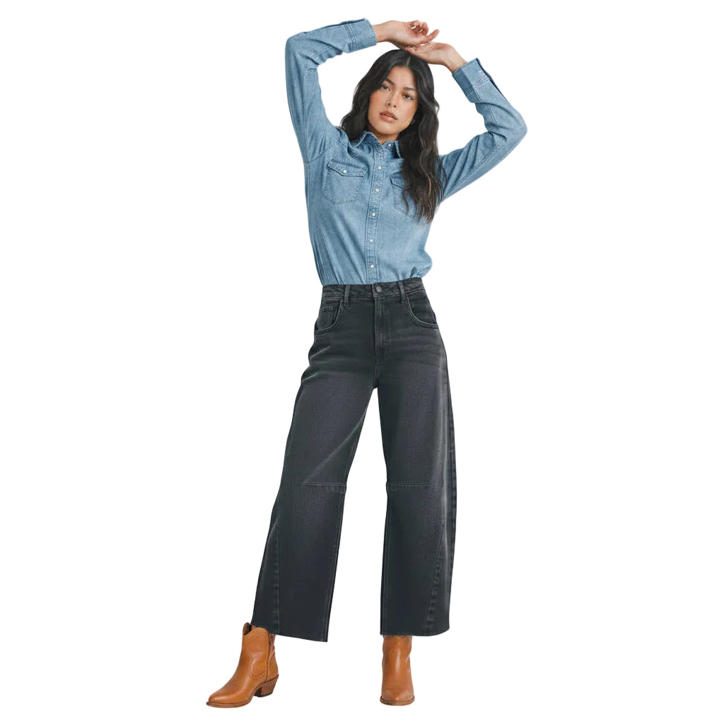 Woman wearing a light blue denim shirt and dark gray jeans on a white background