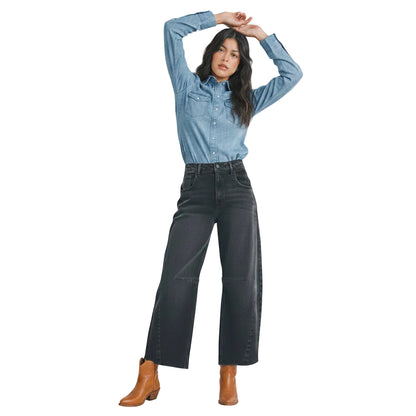 Woman wearing a light blue denim shirt and dark gray jeans on a white background