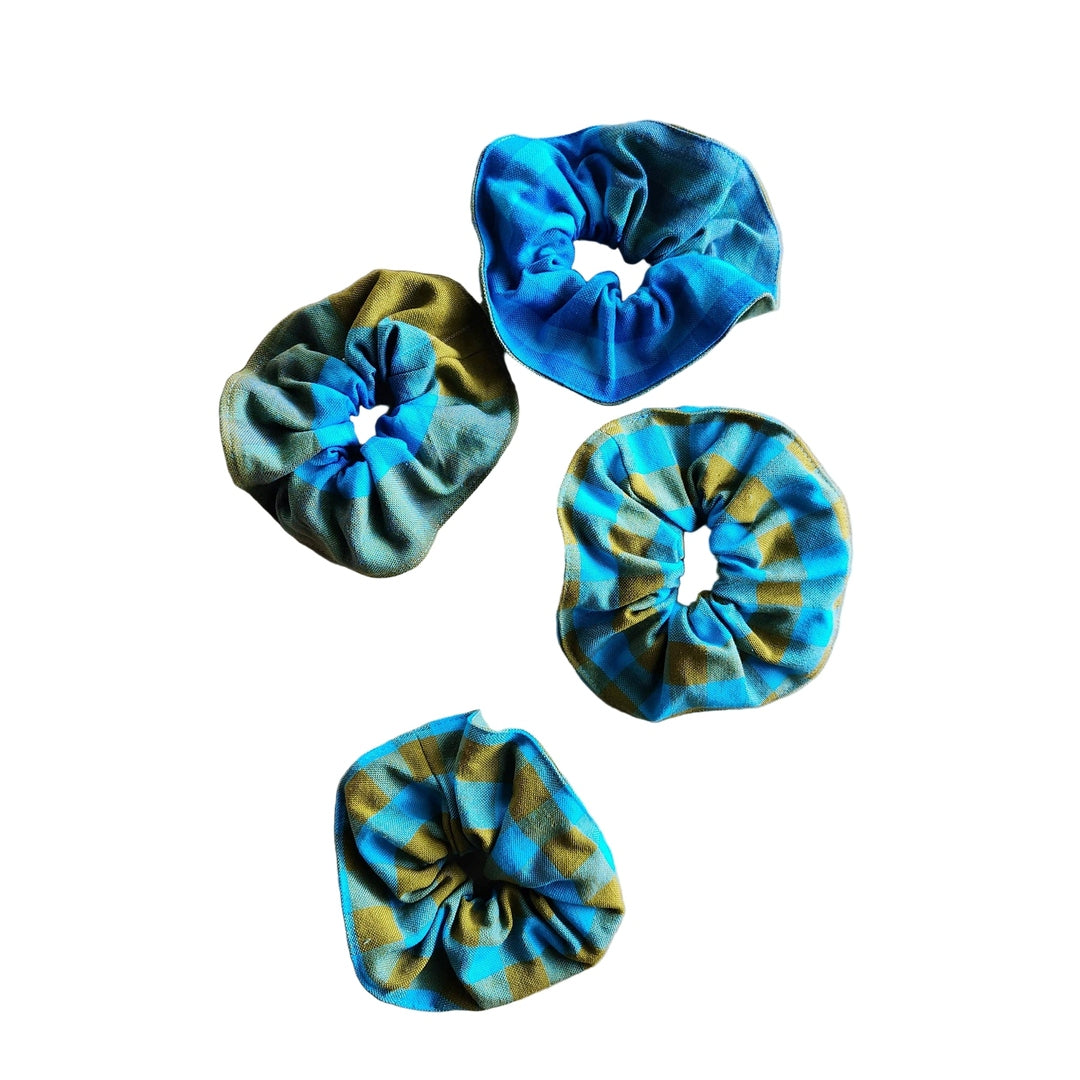Four tie-dye scrunchies in blue and green on a white background