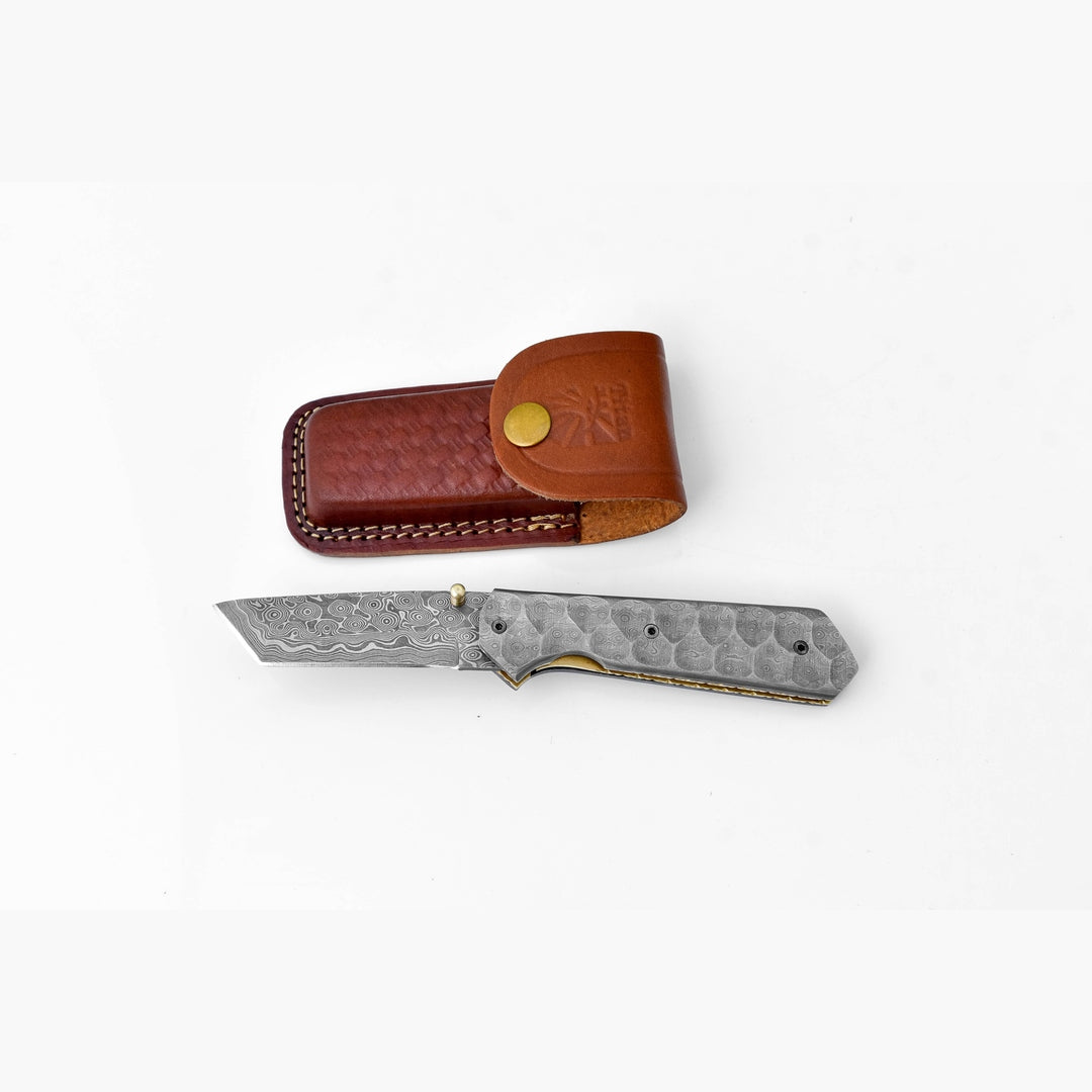 Folding knife with a textured blade and brown leather sheath on a white background