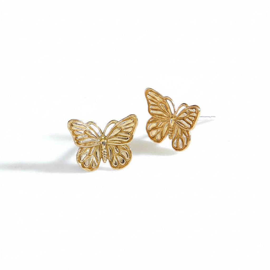 Gold butterfly earrings on a white surface.